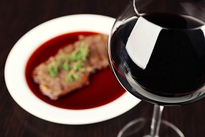 Glass of wine with steak on wooden background
